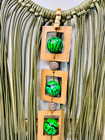 Amazonian Treasures Walking Roots necklace featuring green paxiúba seeds, natural wood frames, and cascading cotton.
