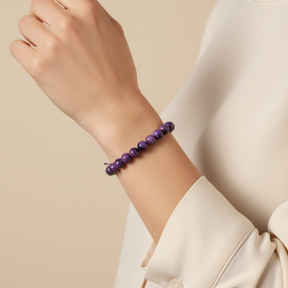 Amazonian Treasures handcrafted purple acai seed stretch bracelet worn on a woman's wrist with a beige blouse.