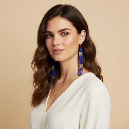 Amazonian Treasures long handmade beaded earrings in blue, white, and black worn by a woman with wavy brown hair.