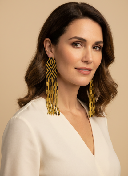 Amazonian Treasures Wai Wai handmade 7-inch long beaded fringe earrings in black and gold geometric patterns on a model